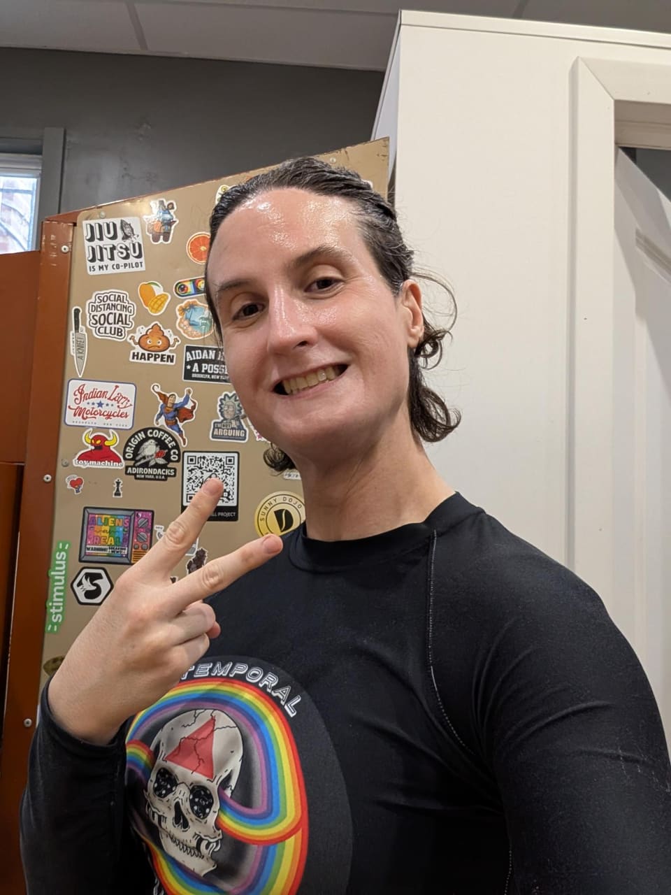 Quinn, the trainer, smiling and making a peace sign in the gym.